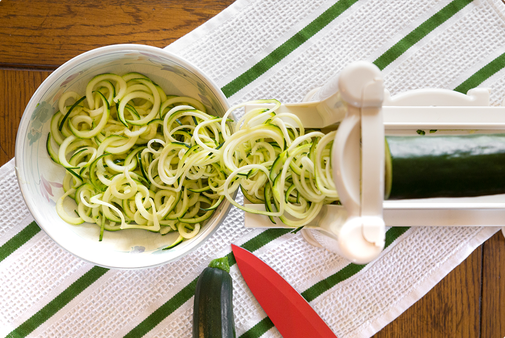 Courgette in spiraliser with spirals in a bowl from above